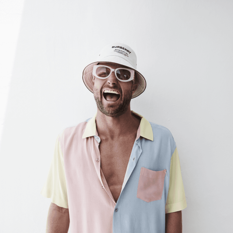Artist laughing in a bucket hat and pastel shirt